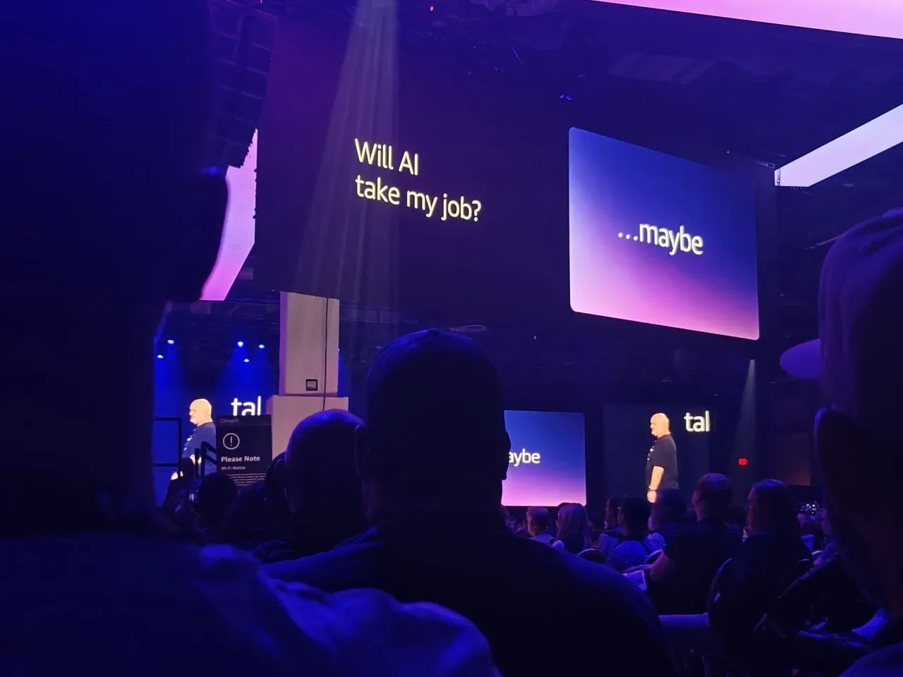 A photo taken from the audience of Werner Vogels' keynote, of a slide asking the question: 'Will AI take my job', and the answer: 'Maybe'.
